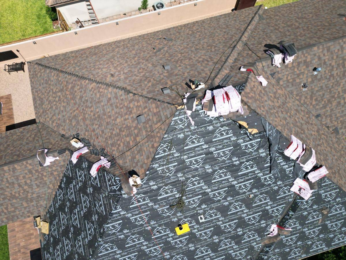 Roofer inspecting a recently installed shingle roof for unsealed tabs and proper nailing”