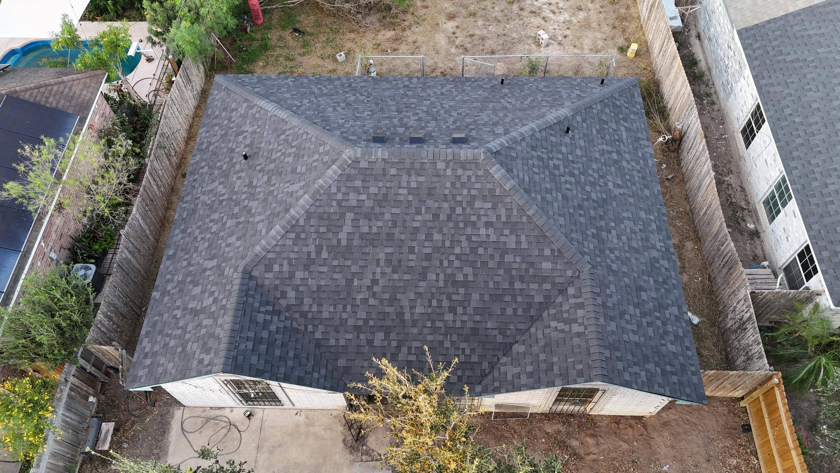 “Newly installed asphalt shingle roof showing slight waviness while shingles are still sealing”